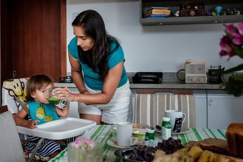 mãe dando suco para filha'