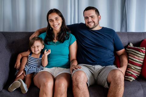 pai mã e filha no sofá de casa olhando para a foto'