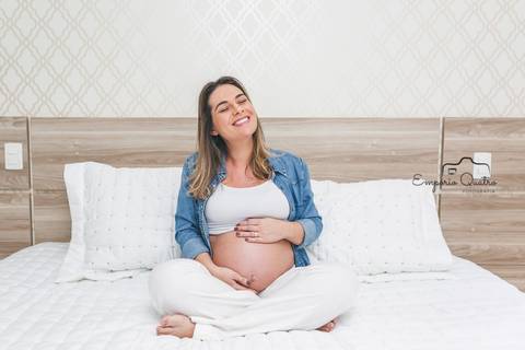 ensaio gestante mãe na cama segurando a barriga'