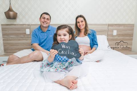 ensaio gestante família na cama filha segurando plaquinha'