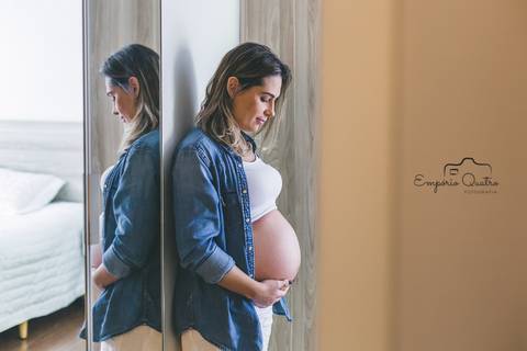 ensaio gestante mãe de costas para espelho segurando a barriga'