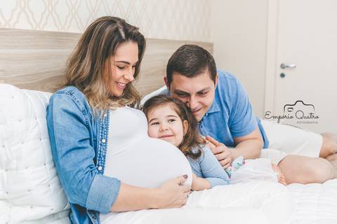 ensaio gestante família reunida na cama filha abraçando barriga da mãe'