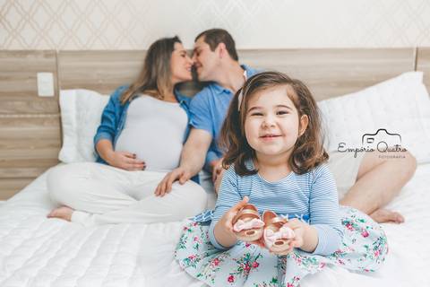 ensaio gestante família reunida na cama filha segurando sapatos e pais se olhando'