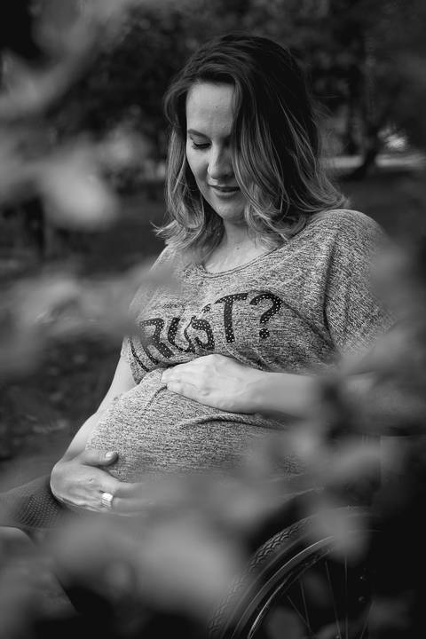 foto em preto e branco com a gestante olhando para a barriga e com as mão sobre a barriga'