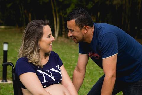gestante cadeirante com seu marido do lado os dois se olhando e sorrindo'