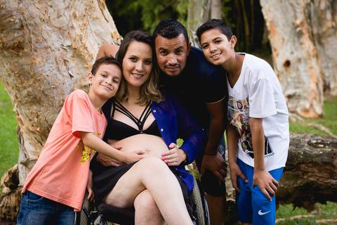 gestante de cadeira de rodas com seu marido e seu filho '