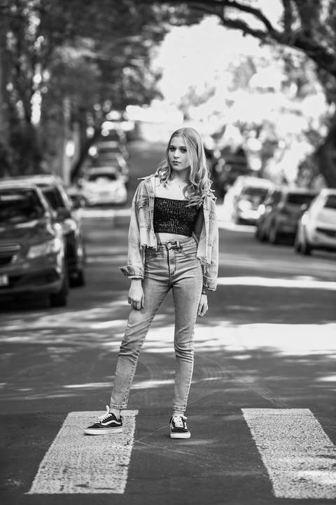 book de 15 anos menina loira com roupas jeans e blusa preta de paetê no meio da rua rua com carros no fundo. Fábio Martins fotografo '