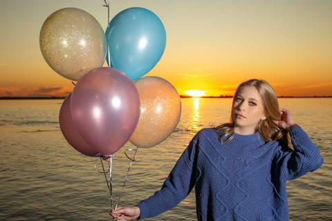 menina calça preta blusa azul com tênis vans ao por do sol na orla do Guaíba com balões coloridos na mão. Fábio Martins fotografo'
