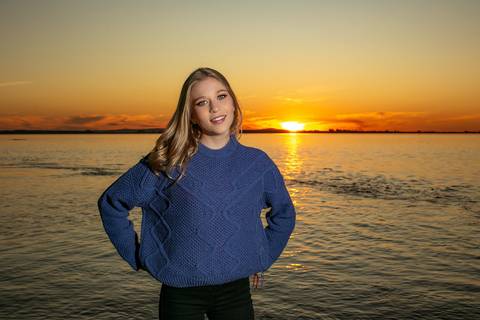 menina calça preta blusa azul com tênis vans ao por do sol na orla do Guaíba com o sol se pondo. Fábio Martins fotografo '