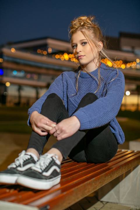 menina calça preta blusa azul com tênis vans sentada ao por do sol na orla do Guaíba na frente do pontal shopping. Fábio Martins fotografo'