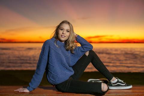 menina calça preta blusa azul com tênis vans sentada ao por do sol na orla do Guaíba. Fábio Martins fotografo '