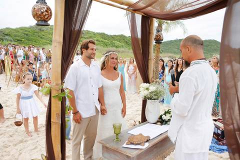 noiva-beijando-noivo-casal-se-beijando-na-praia-noiva-chegando-ao-altar-na-beira-da-praia-convidados-vestimenta-festa-casamento-na-beira-da-praia-do-rosa-sal-e-mar-making-of-noivo-se-arrumando-para-o-casamento-na-praia-do-rosa-em-santa-catarina-fotografia'