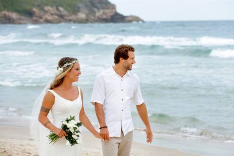 noiva-beijando-noivo-casal-se-beijando-na-praia-noiva-chegando-ao-altar-na-beira-da-praia-convidados-vestimenta-festa-casamento-na-beira-da-praia-do-rosa-sal-e-mar-making-of-noivo-se-arrumando-para-o-casamento-na-praia-do-rosa-em-santa-catarina-fotografia'