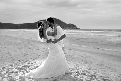 noiva-beijando-noivo-casal-se-beijando-na-praia-noiva-chegando-ao-altar-na-beira-da-praia-convidados-vestimenta-festa-casamento-na-beira-da-praia-do-rosa-sal-e-mar-making-of-noivo-se-arrumando-para-o-casamento-na-praia-do-rosa-em-santa-catarina-fotografia'