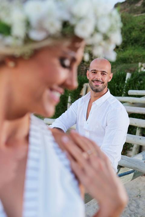 FOTOGRAFIA-NA-PRAIA-DE-GAROPABA-E-PRAIA-DO-ROSA-PRÉ-WEDDING-foto-noiva desfocada-noivo-foco-praia-do-rosa-noivo-de-branco-noiva-sorrindo-em-segundo-plano-foto-desfocada-praia-do-rosa-praia-de-garopaba-santa-catarina-noivos-noiva-noivo-casamento-praia'