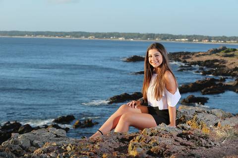 Fotografia-de-Street-Book-de-15-anos-na-praia-de-Punta-del-Este-em-Maldonado-no-Uruguai-modelo-sentada-nas-pedras-sorrindo-mar-no-fundo-modelo-na-praia-sentada-modelo-sentada-nas-pedras-da-praia-book-de-15-anos-na-praia-book-quinze-praia-punta-del-este'