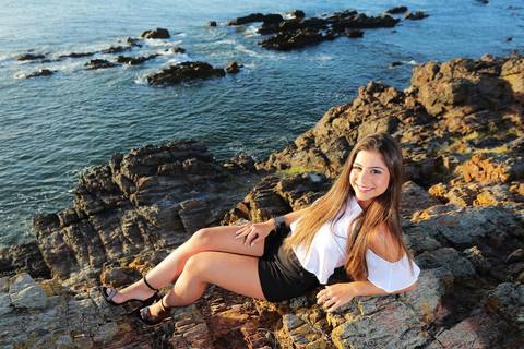 Fotografia-de-Street-Book-de-15-anos-na-praia-de-Punta-del-Este-em-Maldonado-no-Uruguai-modelo-sentada-sorrindo-pedras-punta-del-este-modelo-sentada-nas-pedras-com-mar-atras-em-maldonado-book-de-quinze-anos-na-praia-book-15-anos-diferente-debutante-praia'