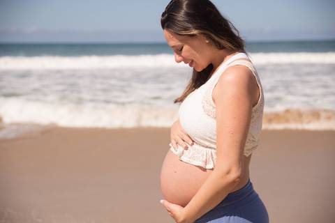 foto de grávida segurando a barriga na praia. ensaio gestante'