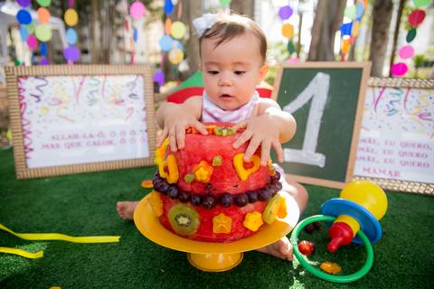 foto do bebê comendo o bolo de frutas no cenário colorido. ensaio smash the cake smash the fuit'
