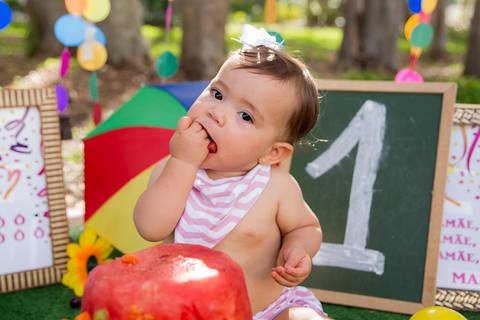 foto do bebê comendo o bolo de frutas no cenário colorido. ensaio smash the cake smash the fuit'