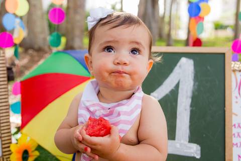 foto do bebê comendo o bolo de frutas no cenário colorido. ensaio smash the cake smash the fuit'
