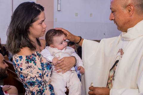padre com a mão na cabeça do bebê no colo da mãe fotografia batizado'