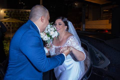 Noivo ajudando a noiva ao sair do carro.'