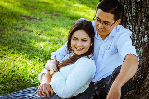 Ensaio fotográfico do casal. Esta foto eles se abraçam com carinho sentindo uma brisa suave. '