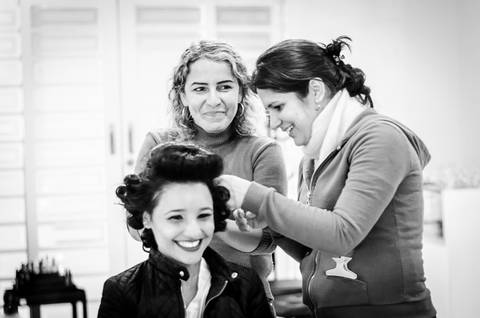 Fotografia de casamento do making of da noiva no salão de beleza no dia da noiva, com a equipe arrumando da cabeleireira e equipe sorrindo arrumando o cabelo. Em Araçatuba SP'