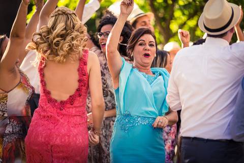 Fotografia de casamento com cerimônia e festa e recepção ao ar livre durante o dia no Califórnia Eventos em Araçatuba SP. Os convidados na pista de dança com a música do DJ dançando. A Mãe do noivo pulando de vestido longo azul claro.'