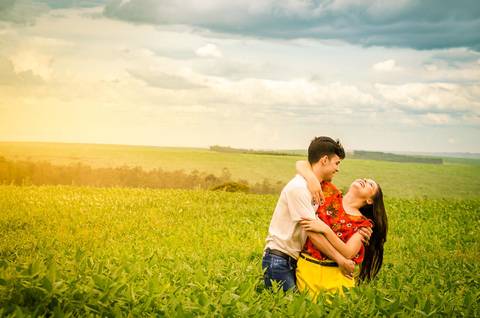 Fotografia do noivo e da noiva dançando em meio a uma plantação de soja com céu azul em Maringá, PR'
