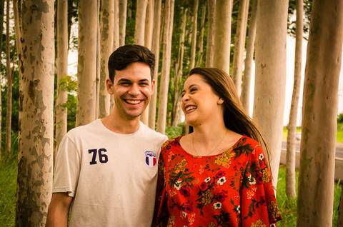 Fotografia do noivo e da noiva no pre casamento sorrindo em meio a uma plantação de eucaliptos em Maringá, PR'