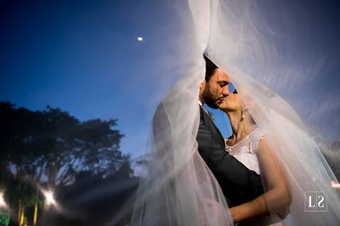 noivos-se-beijando-com-veu-ao-vento'