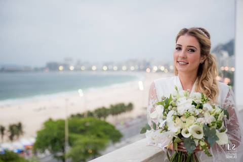 noiva posando na janela com vista para a praia'