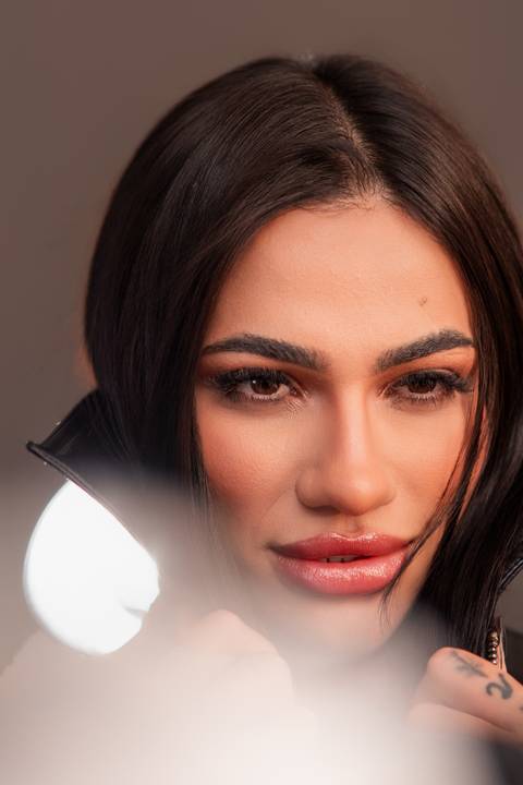 Ensaio feminino estúdio Curitiba. Close expressivo no rosto, luz frontal suave, fundo cinza neutro. Marco Lourenço Fotografia.'