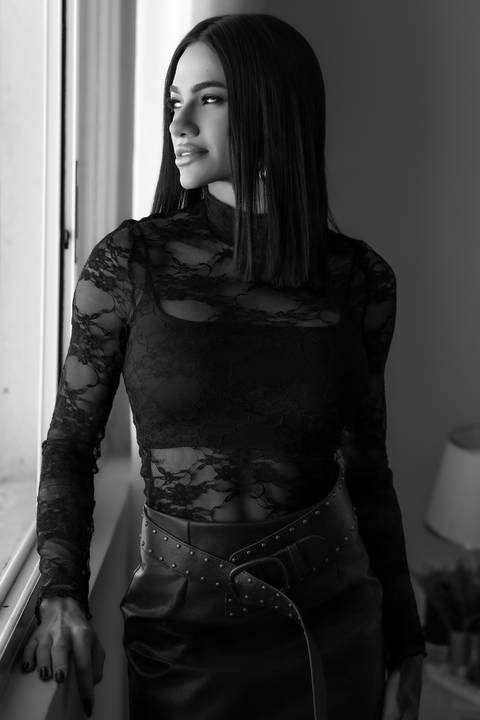 Ensaio feminino Curitiba. Mulher com roupa rendada em pé, pose confiante, fundo cinza neutro. Marco Lourenço Fotografia.'
