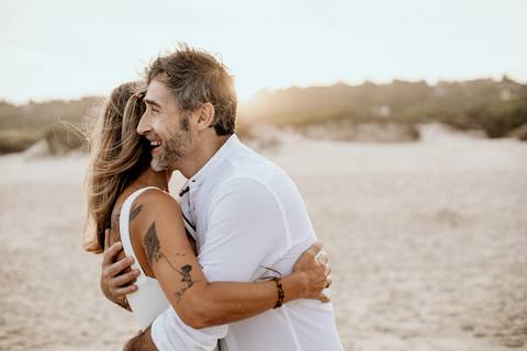 casal se abraçando na praia ao nascer do sol'