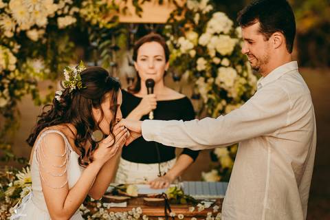 NOIVA BEIJANDO A MÃO DO NOIVO DEPOIS DE COLOCAR AS ALIANÇAS'