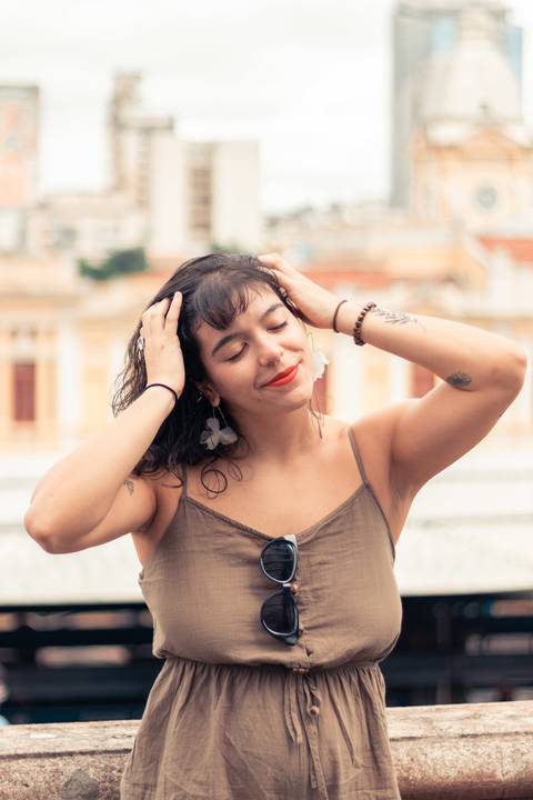 foto tirada em Belo Horizonte com a modelo de frente segurando o cabelo com ambas as mãos e sorrindo'
