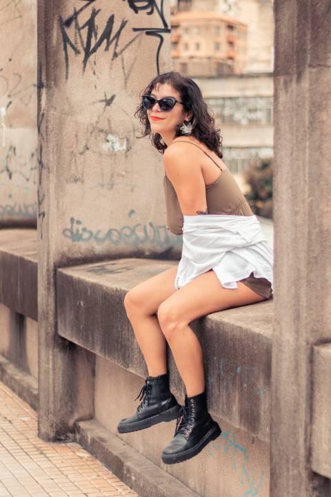 Modelo sentada no parapeito do viadulto santa tereza com um sorriso no rosto '