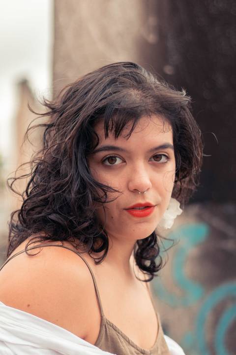 Retrato com modelo de olhando de lado, séria, olhar marcante, brincos grandes e cabelo solto'