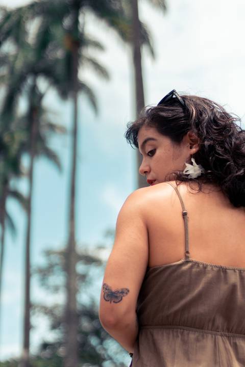 Retrato com a mulher olhando por cima do ombro e mostrando a tatuagem no braço'