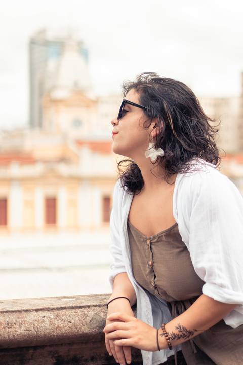 foto tirada em Rua Aapucaí com a modelo com o sorriso leve, olhando de lado com óculos escuro'