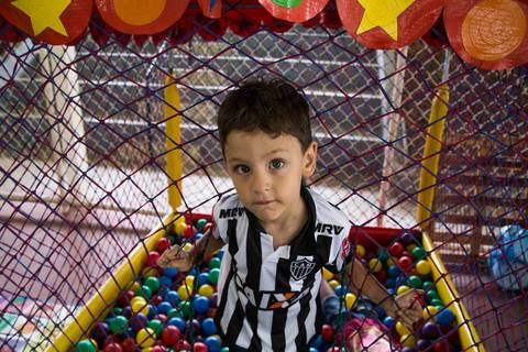Foto do aniversariante, em um piscina de bolinhas, colocada para diversão da garotada em sua festa de aniversário.'