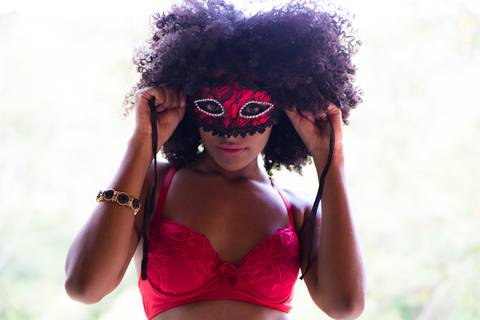 Fotografia sensual, com a modelo experimento uma máscara e usando um sutiã vermelha de rendas.'