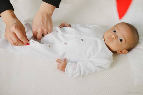 Fotografia de mãe trocando bebê no berço'