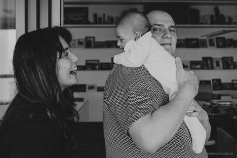 Filho sorrindo para a mãe no colo do pai'