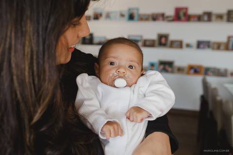 Retrato de bebê com chupeta no colo da mãe '