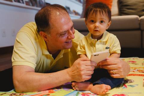 Retrato de pai mostrando celular para o filho'