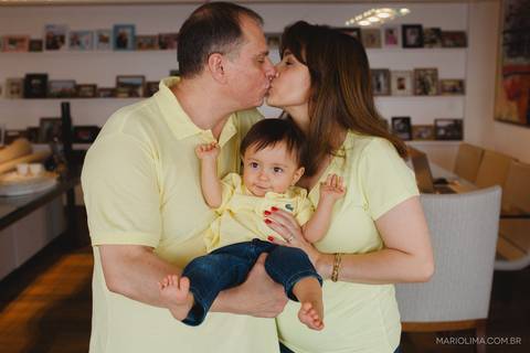 Fotografia de pais se beijando com criança no colo'